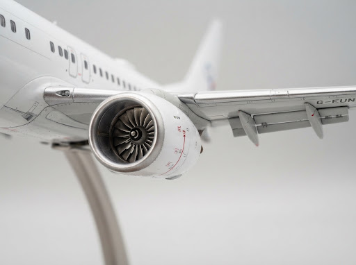 Macro close-up photography of diecast scale model turbine engine fan blades with nacelle stencil markings and flap track fairing